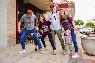 Family of sports fans wearing Aggie gear in Downtown Bryan Texas