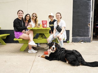 A group of friends and a dog sit by the patio of Blackwater Draw Brewery.