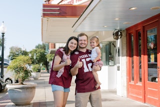 Aggie family smiling in Historic Downtown Bryan during Gameday on Main in Bryan, Texas