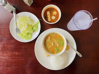 An overhead image of panang curry, salad, and tofu soup