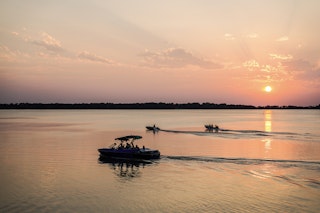 Three boats traverse across the sunset-hued waters of Lake Bryan.