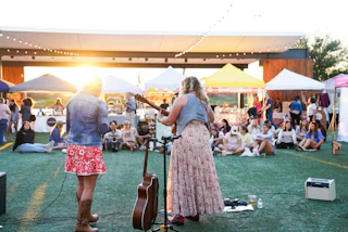 two singers performing to a crowd on an outdoor pavilion