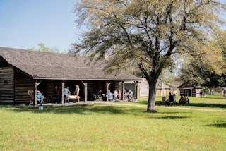 People standing in front of dog-trot cabin at Boonville Heritage Park